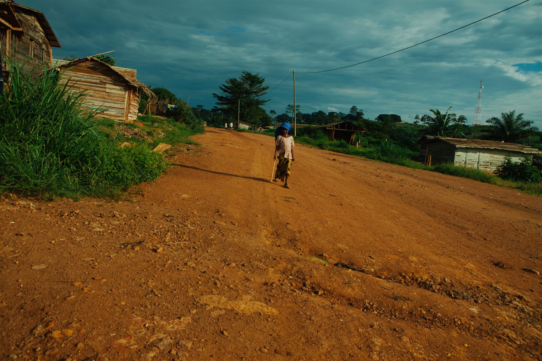 A figure walking along a red road in My Africa, My Cameroon